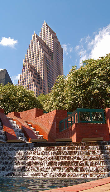 A modern highrise office building is contrasted against a tranquil waterfall in an urban park in downtown Houston, Texas.