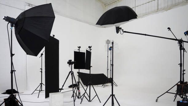 istock Studio video production lighting set. Behind the scenes shooting production set up by crew team camera and equipment in studio. Video production filming or commercial movie film live streaming online. 1399874472