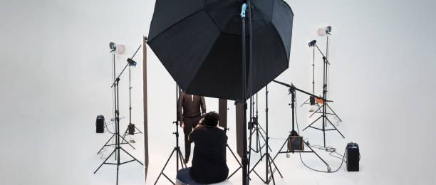 istock Studio video production lighting set. Behind the scenes shooting production set up by crew team camera and equipment in studio. Video production filming or commercial movie film live streaming online. 1399874561