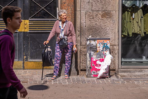 Elderly woman taking a break in a shopping street on a sunny day of spring in the pedestrian zone in the center of Copenhagen