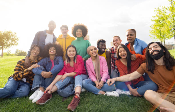 gran grupo de jóvenes multirraciales diversos en el parque, celebrando la vida juntos disfrutando de felices fiestas. estilo de vida, viajes, unión y concepto de alegría - inmigrante fotografías e imágenes de stock