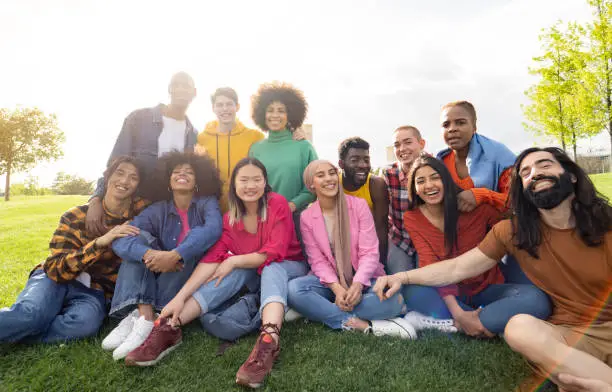 Photo of large group of diverse multiracial young people in the park, celebrating life together enjoying happy holidays. lifestyle, travel, togetherness and joy concept