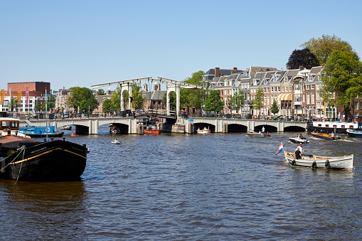The River Amstel with Magere Brug city bridge on a summer day in Amsterdam, The Netherlands