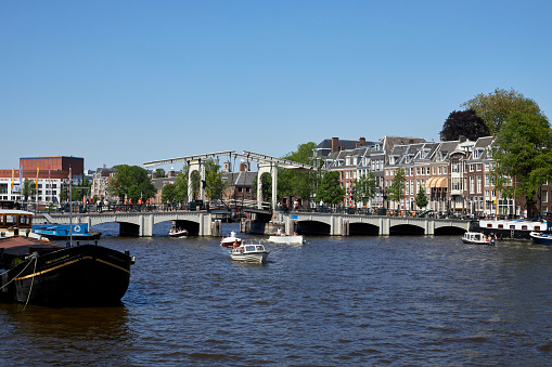 The River Amstel with Magere Brug city bridge on a summer day in Amsterdam, The Netherlands