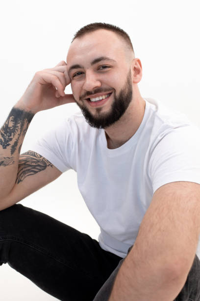 istock Vertical tattooed laughing handsome brunette man sitting in studio. Male hair loss problem. After transplanting. Closeup 1399878327