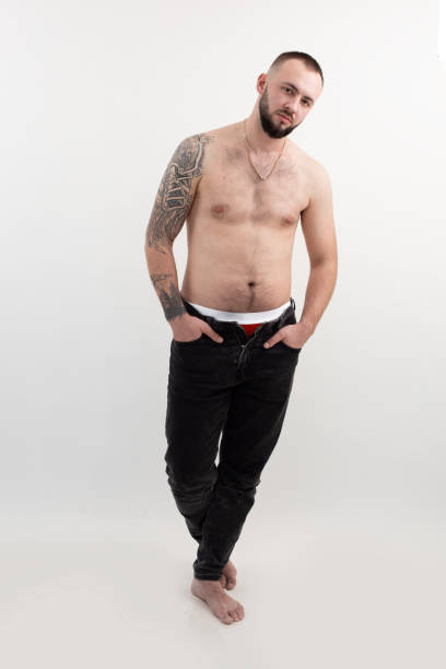 uomo bello e brutale sicuro con barba e tatuaggio, senza camicia e in topless, su sfondo bianco isolato. guarda la fotocamera - stubble men tattoo sensuality foto e immagini stock