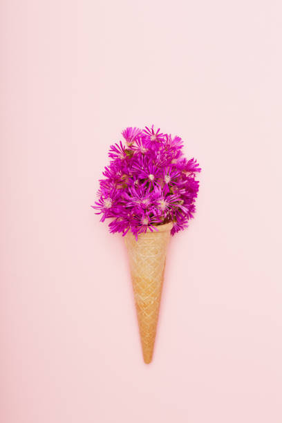 istock Fresh wildflowers in ice cream cone on pink background flat lay 1399879045
