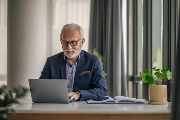 istock Senior businessman using laptop while working at desk in office 1399879336