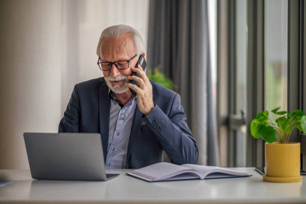 istock Confident entrepreneur talking on mobile phone while using laptop at office desk 1399879345