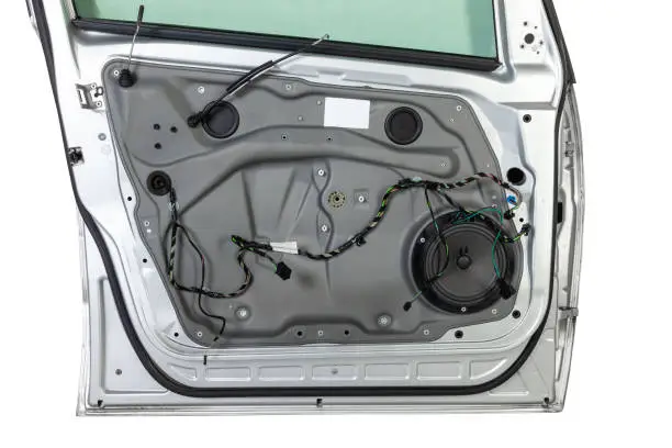 The multiband speaker of the audio system in the door with the car trim removed is connected with a connector for high-quality sounding of acoustics during music playback.