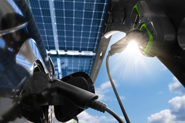Electric car is charged from a charging station that takes energy from solar panels. Solar carport. Close up stock photo