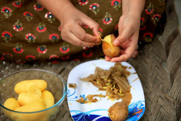 Rural women sitting on charpai at home and peeling boiled potato.