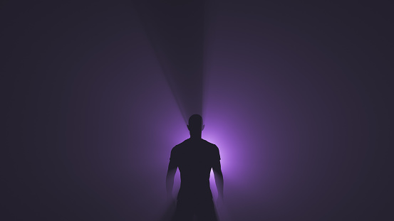 Silhouette of a man in the rays of a purple spotlight.