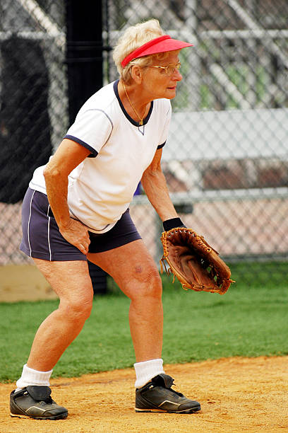 Senior Woman Playing Softball Senior woman catching for senior softball league. old baseball stock pictures, royalty-free photos & images