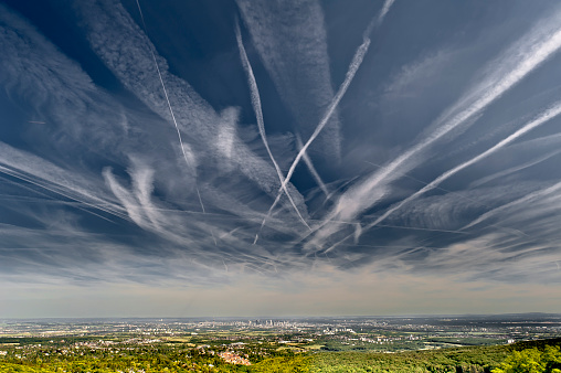 Dramatic cloudy sky with contrails over the Rhine-Main area with the skyline of Frankfurt am Main on the horizon and the Vordertaunus with the city of Kronberg in the foreground