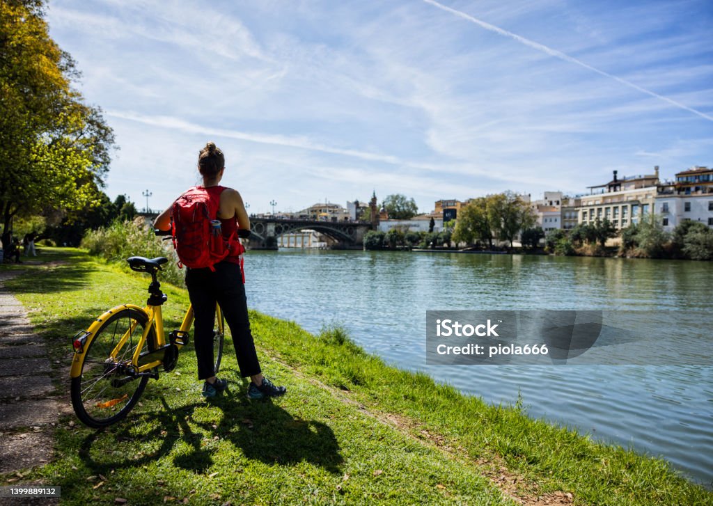 Tourist life in Seville, Andalusia: woman enjoys the city by bicycle City life in Seville, Andalusia, during a summer day. Seville is the capital city of Andalusia, Spain. A tourist woman enjoy the city riding a bicycle Seville Stock Photo