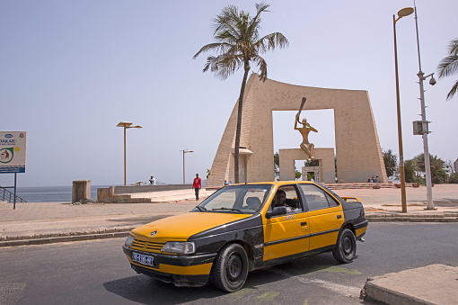 Dakar, Senegal - May 30, 2014: Taxi circulating on the promenade of La Corniche, near of the Door of the Millennium
