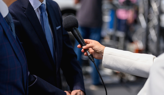Unrecognizable female journalist holding microphone, interviewing politician or business person, Nikon Z7