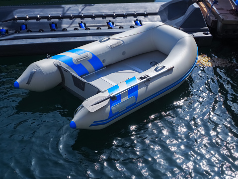 An inflatable gray-blue motor boat is moored in sea bay with shining water
