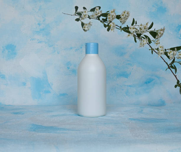 bottle for cosmetic products without a label. facial skin care concept. branch with flowers on top. texture - liquid soap blue plastic textile imagens e fotografias de stock