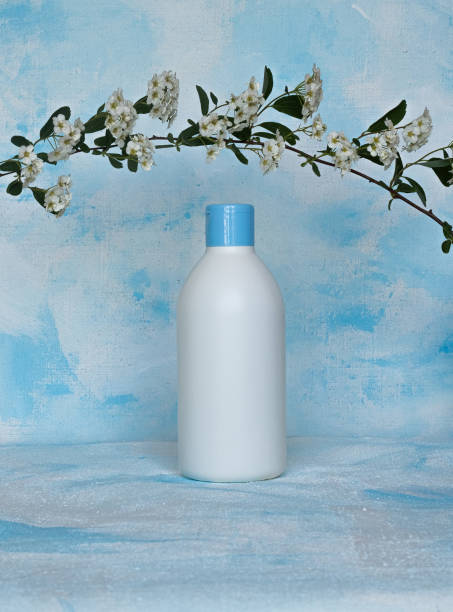 bottle for cosmetic products without a label with a flower branch. facial skin care concept .texture - liquid soap blue plastic textile imagens e fotografias de stock