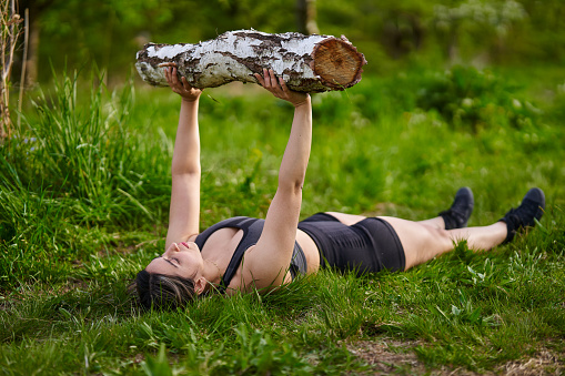 Strong size plus indian woman doing fitness workout outdoor with a log
