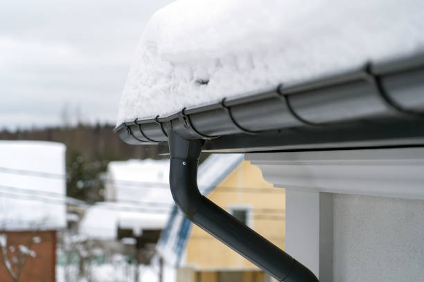 istock Metal Downpipe system, Guttering System, External downpipes and drainage pipes under snow. Corner of house with roof made of gray metal tiles and gutter covered with thick layer of snow in winter. 1399907012