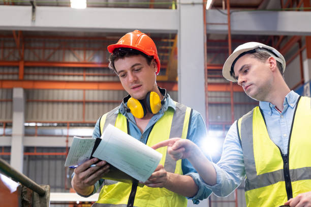 istock Selective focus at Caucasian men mechanical engineer, wearing safety equipment. While doing machine maintenance and safety control inside of factory area. With blurred background of heavy machine. 1399909301