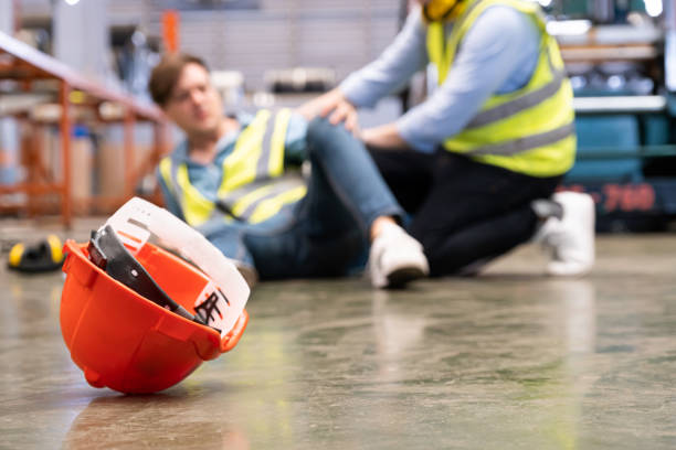 focalisation sélective au chapeau, les hommes travailleurs se sentent douloureux et blessés par l’accident qui se produit à l’intérieur de l’usine industrielle tandis que son collègue vient donner une aide d’urgence et de l’aide. accident en - tomber photos et images de collection