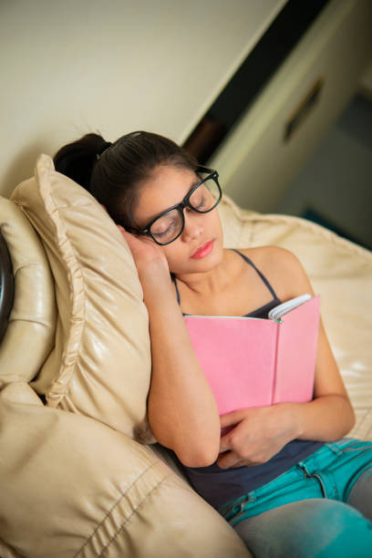 istock Young woman falls asleep on couch reading a book. 1399911941