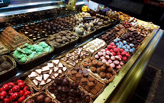 A close up of a shop window of a chocolate factory in Garmisch in Southern Germany. They create and produce varied versions of some beautifully presented chocolates and sweet treats. In the window is multiple variations of toppings and flavours.