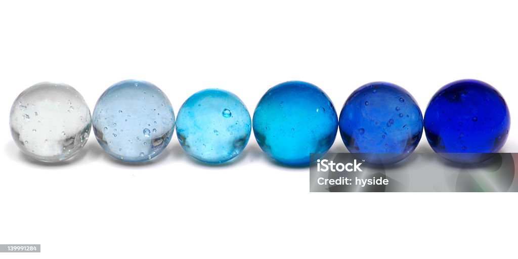 Blue marbles in a graduated row A Row of Clear Marbles in Progressive Shades of Blue. Marbles Stock Photo