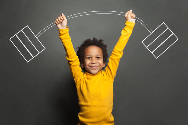 Funny strong black kid with barbell in her hands on chalkboard background