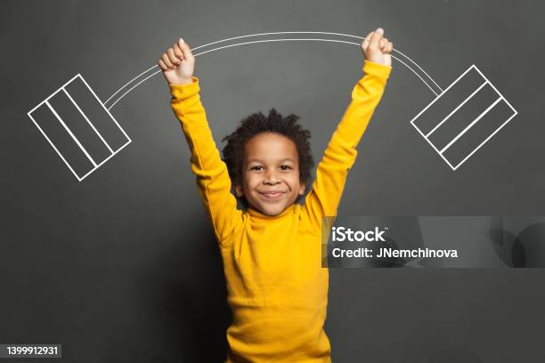 Funny Strong Black Kid With Barbell In Her Hands On Chalkboard Background Stock Photo - Download Image Now