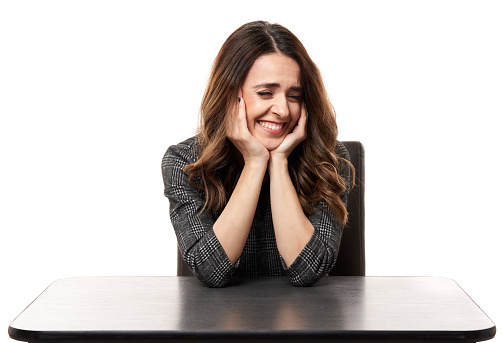 Young woman laughing at a joke, sitting on her desk, isolated on white background