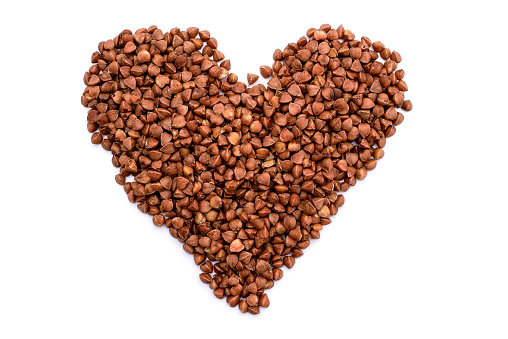Heart made of buckwheat grains isolated on white background