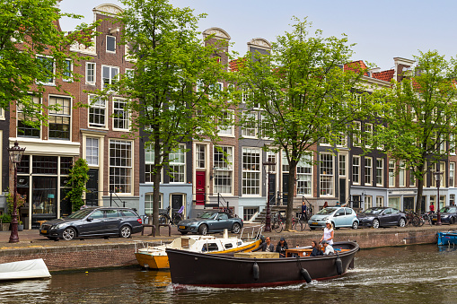 Amsterdam, The Netherlands on june 12, 2016; Pleasure boat sail on the Prinsengracht along beautiful stately canal houses with their characteristic facades.