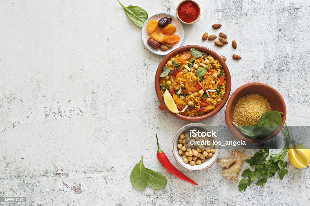 Vegan Moroccan Couscous with Chick Peas, spinach, dried apricots and date fruit. Traditional African or middle eastern dishes assortment. Vegan Moroccan Couscous with Chick Peas, spinach, dried apricots and date fruit. Traditional African Tajine dish. Flat layot Tajine Stock Photo
