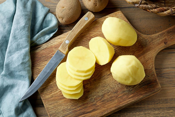fresh raw peeled potatoes fresh raw peeled sliced potatoes on rustic wooden kitchen cutting board, top view prepared potato stock pictures, royalty-free photos & images
