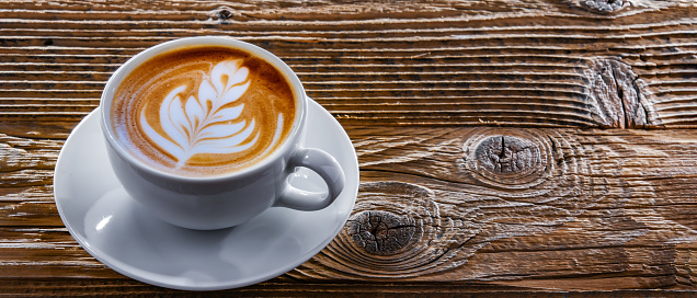 A cup of coffee on an old wooden table.