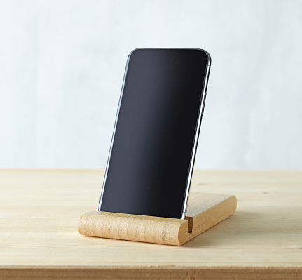 smartphone in wood stand on light wooden table