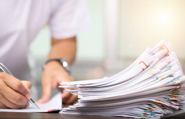 istock Man in white shirt sign contract agreement documents in Stack of Group report papers clipped in color clips in fair light, business, legal law and education concept 1399924278