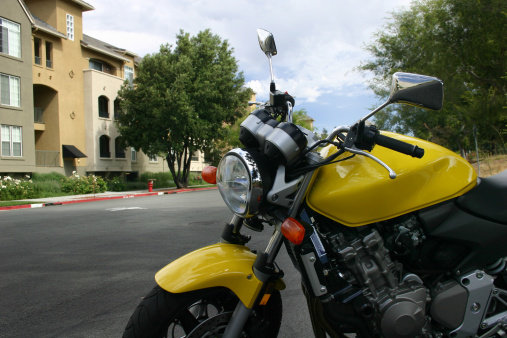 Yellow motorcycle infront of a luxury apartment complex.