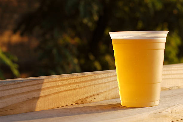 Cold Cup of Beer on a Deck Rail A cold beer in late afternoon sun quench your thirst pictures stock pictures, royalty-free photos & images