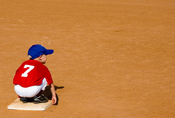 It's Lonely on Second Base Little boy in a blue cap, red shirt and white pants waits for action in a TBall baseball game. youth baseball and softball league photos stock pictures, royalty-free photos & images