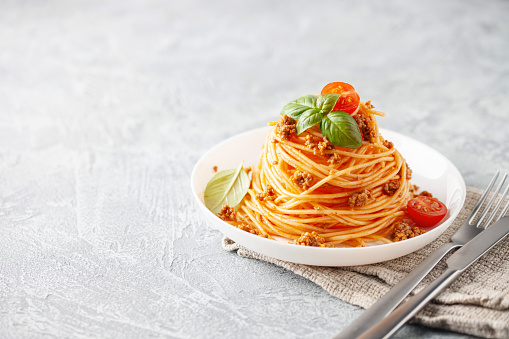 Pasta Spaghetti Bolognese in white plate on gray background. Bolognese sauce is classic italian cuisine dish. Popular italian food.