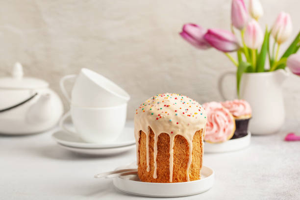 gâteaux de pâques kulich, tulipes et ustensiles blancs pour une cérémonie du thé sur fond lumineux. concept de vacances - tea cake photos et images de collection