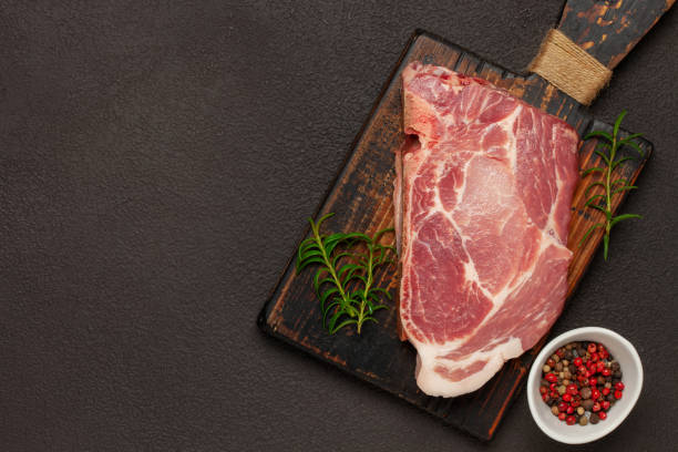 istock Raw beef steak with spices on a dark board. Top view 1399928511