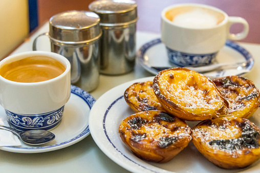 Cups of coffee with milk and Belem cakes typical of Lisbon, Portugal