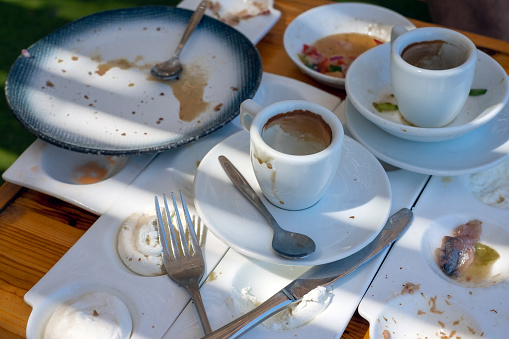 finished dinner and dirty dishes on a messy table, outdoor closeup